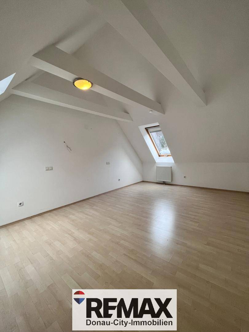 Helles Schlafzimmer im Dachgeschoss mit Schrägdach und einem Dachfenster.