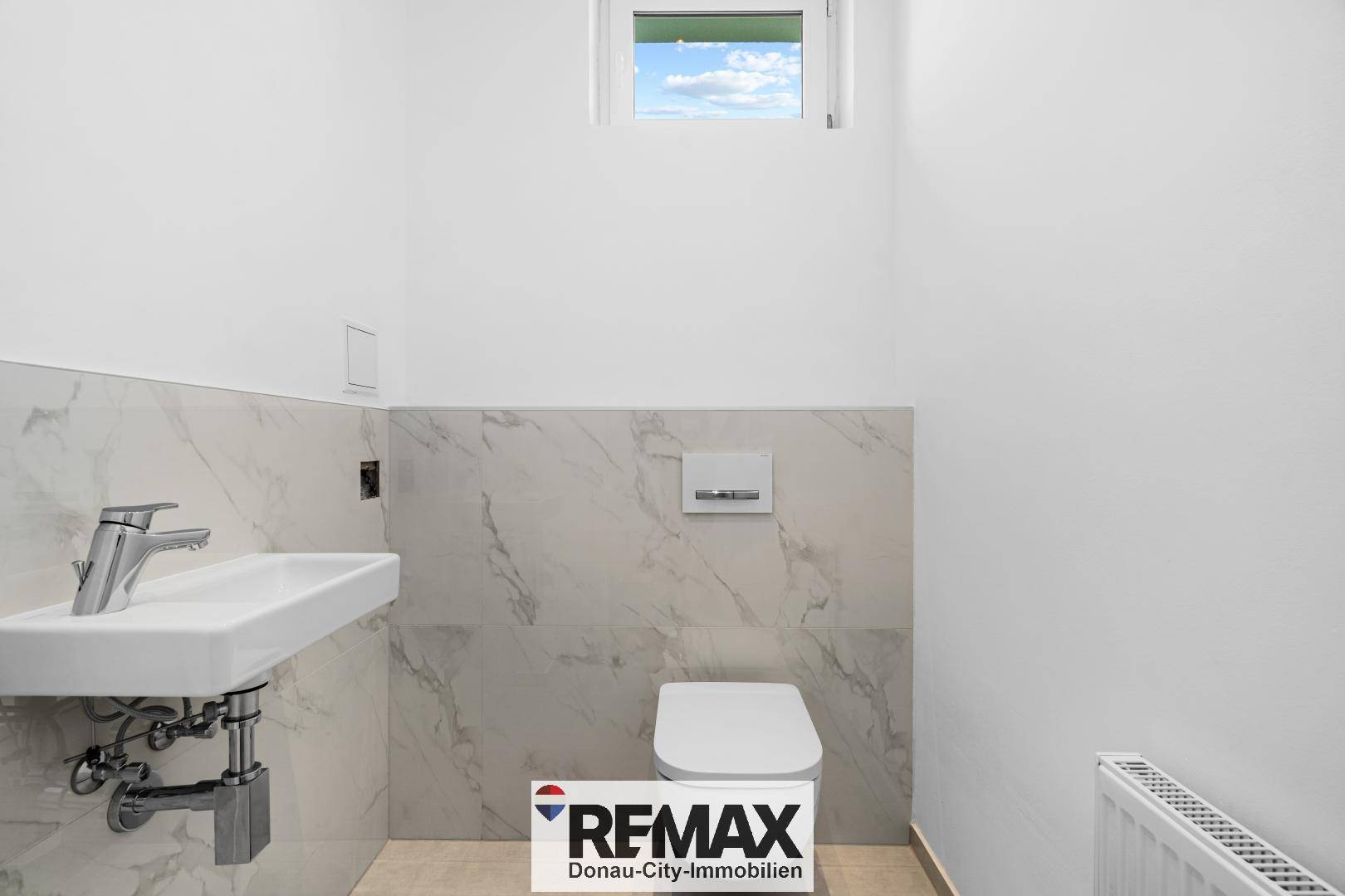 Kleines Gäste-WC mit modernem Waschbecken, Wand-WC und Fenster.