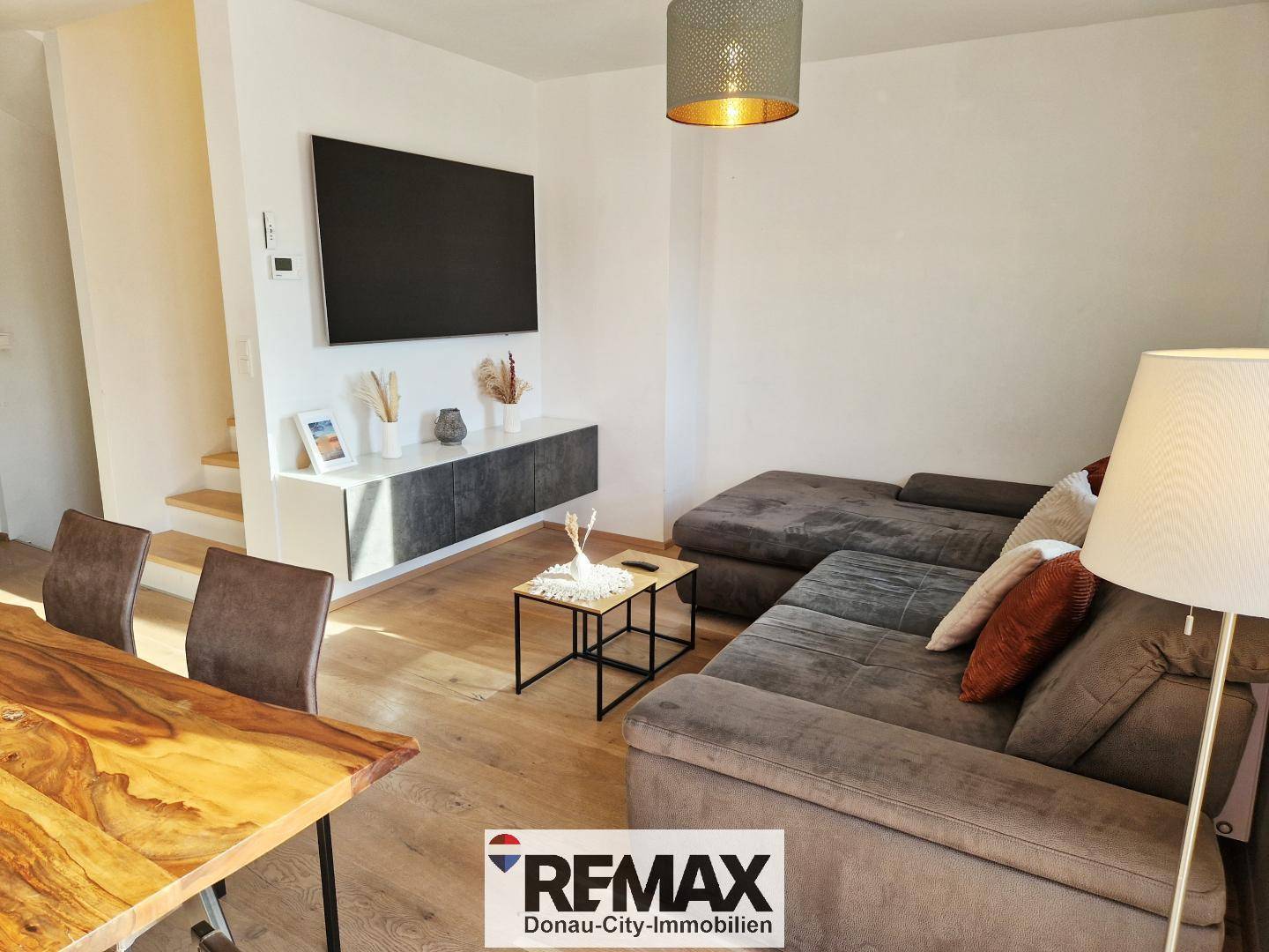 Gemütlicher Wohnbereich mit großem Ecksofa, Wandfernseher und modernem Couchtisch.