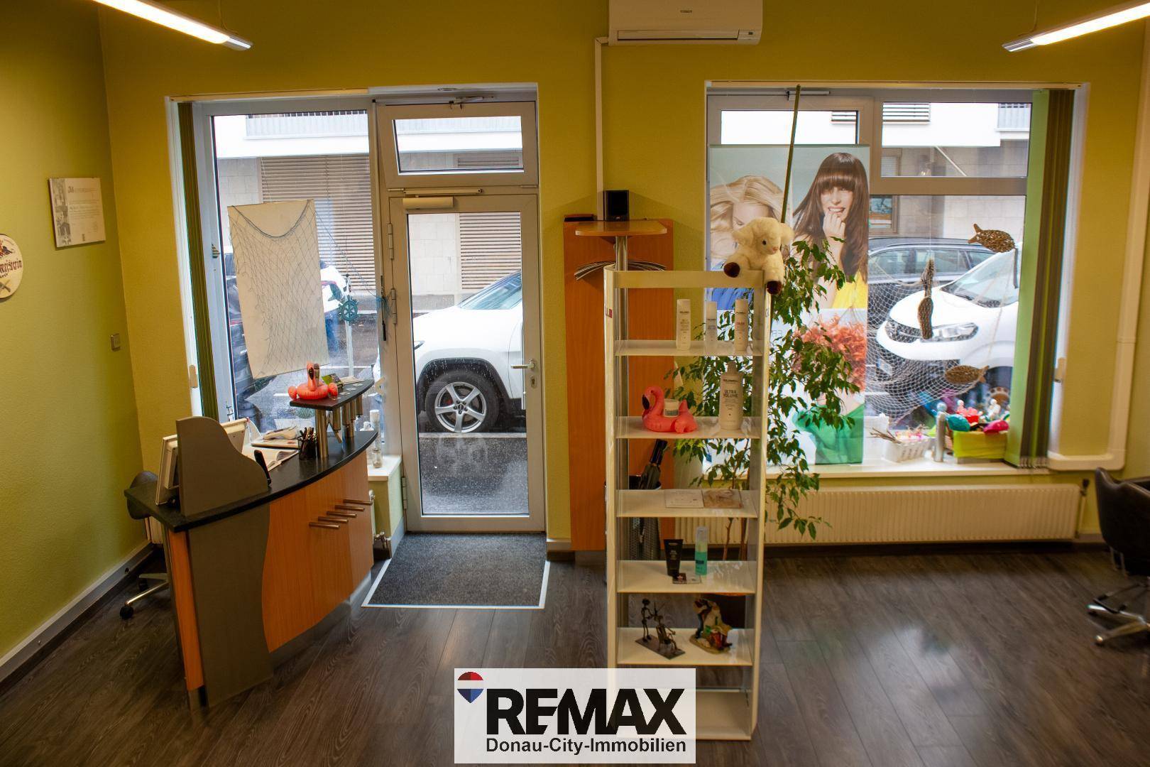Eingangsbereich eines Geschäfts mit Rezeption, großen Schaufenstern und Blick auf die Straße.