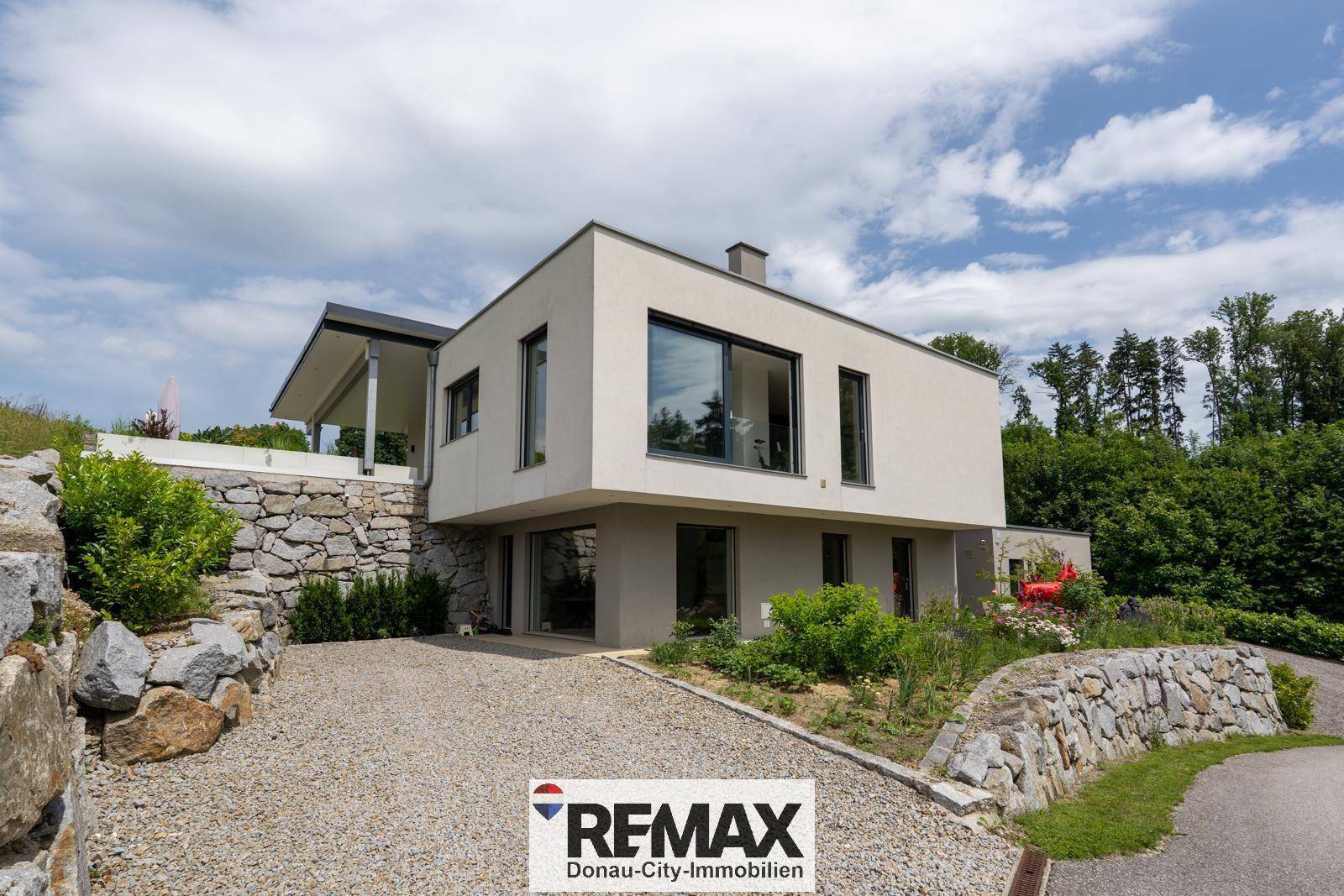 Modernes Einfamilienhaus mit großen Fenstern und überdachtem Außenbereich.