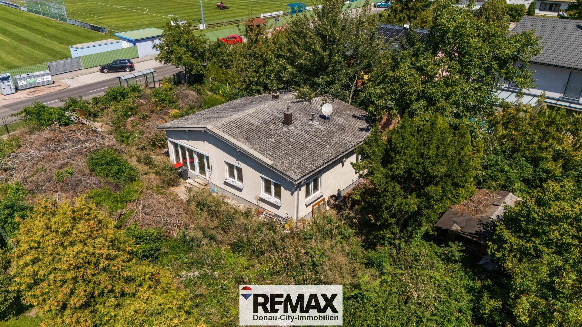 Vogelperspektive des Hauses mit großem Grundstück und angrenzendem Sportplatz in der Ferne.
