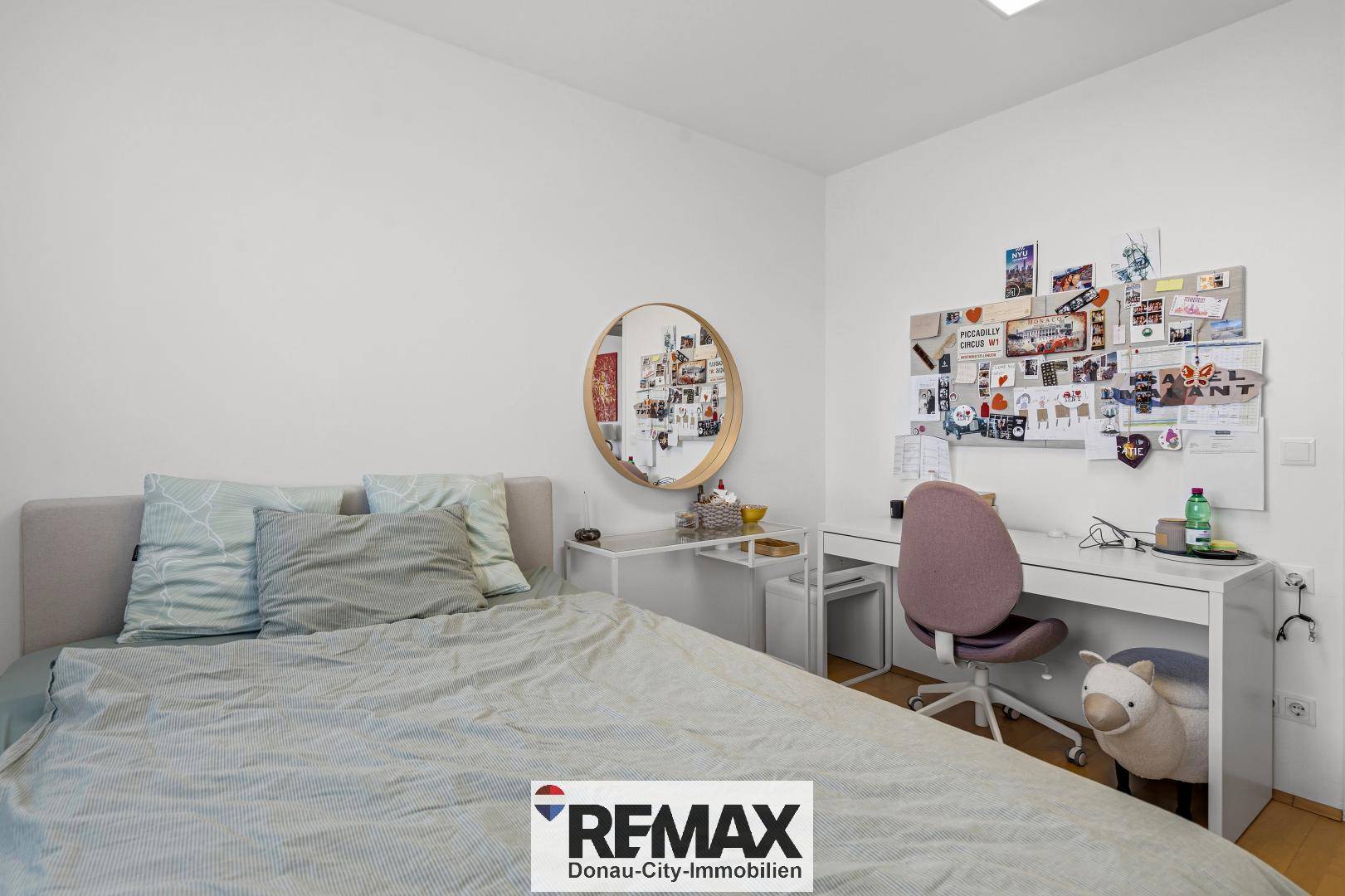 Gemütliches Schlafzimmer mit Schreibtisch, Spiegel und persönlicher Dekoration.