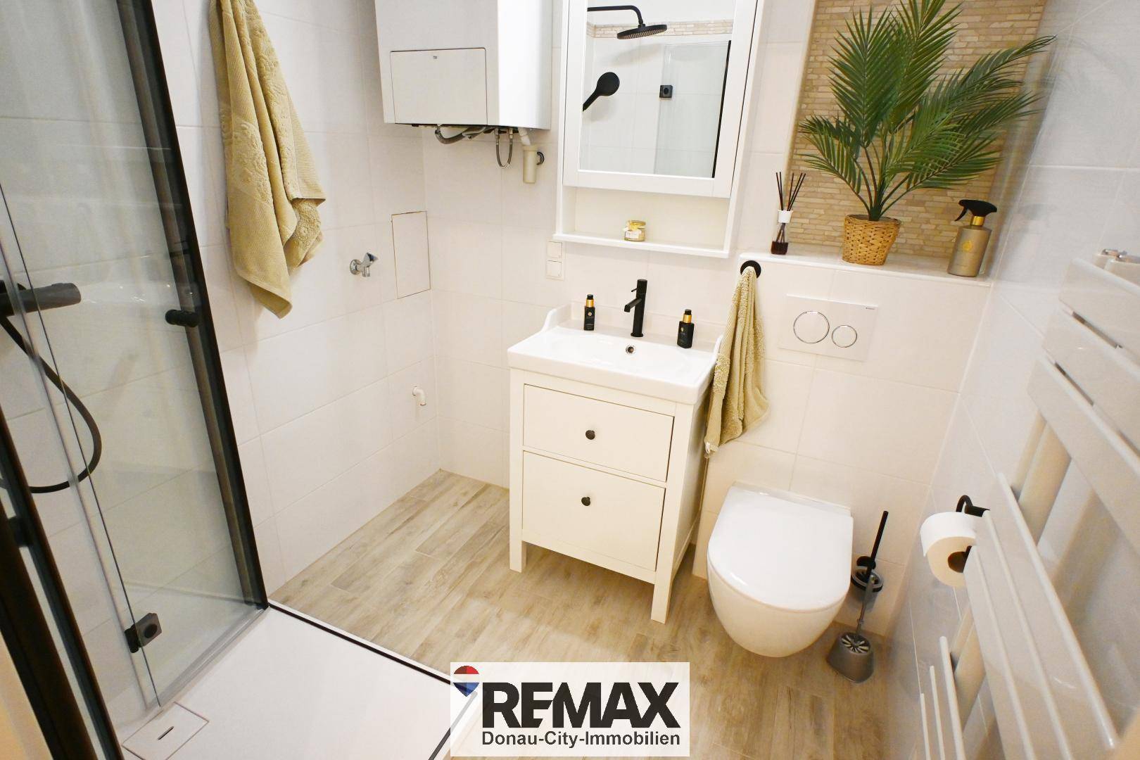 Modernes Badezimmer mit Duschkabine, Waschtisch und beheiztem Handtuchhalter.