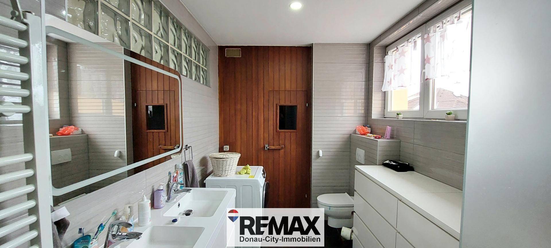 Badezimmer mit Doppelwaschbecken, Toilette und Waschmaschine, gut ausgestattet.