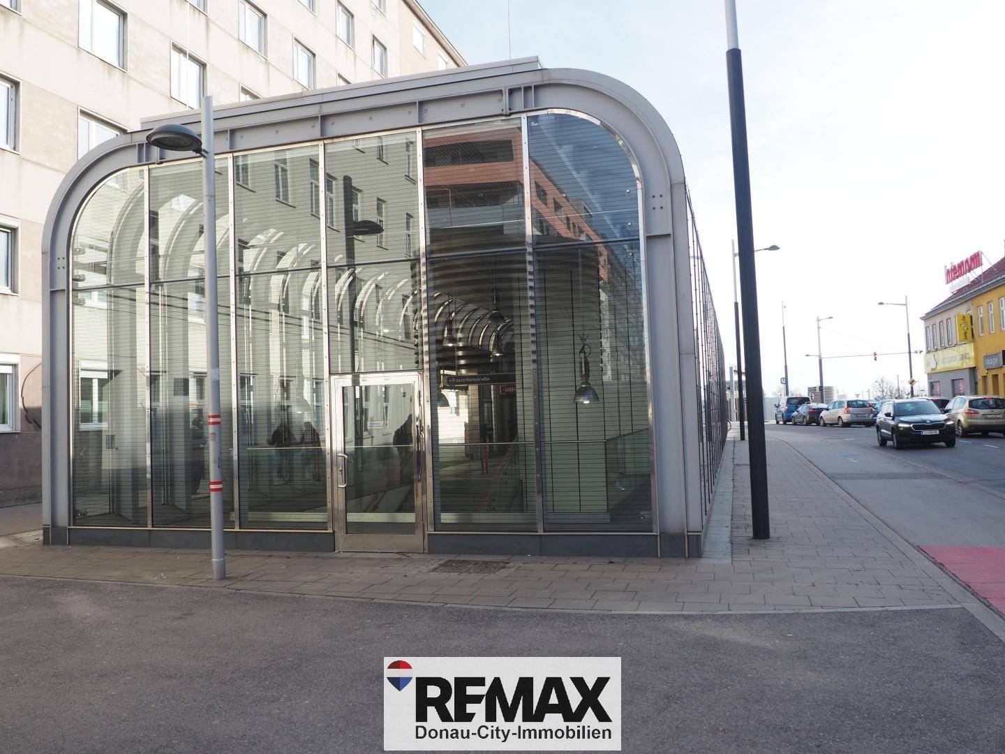 Modernes Gebäude mit gewölbter Glasfassade an einer städtischen Straße, reflektiert die Umgebung.