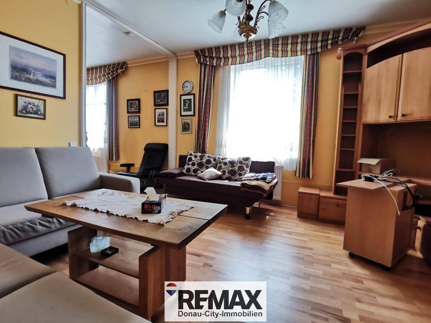 Gemütliches Wohnzimmer mit Holzmöbeln, Parkettboden und gelben Wänden.
