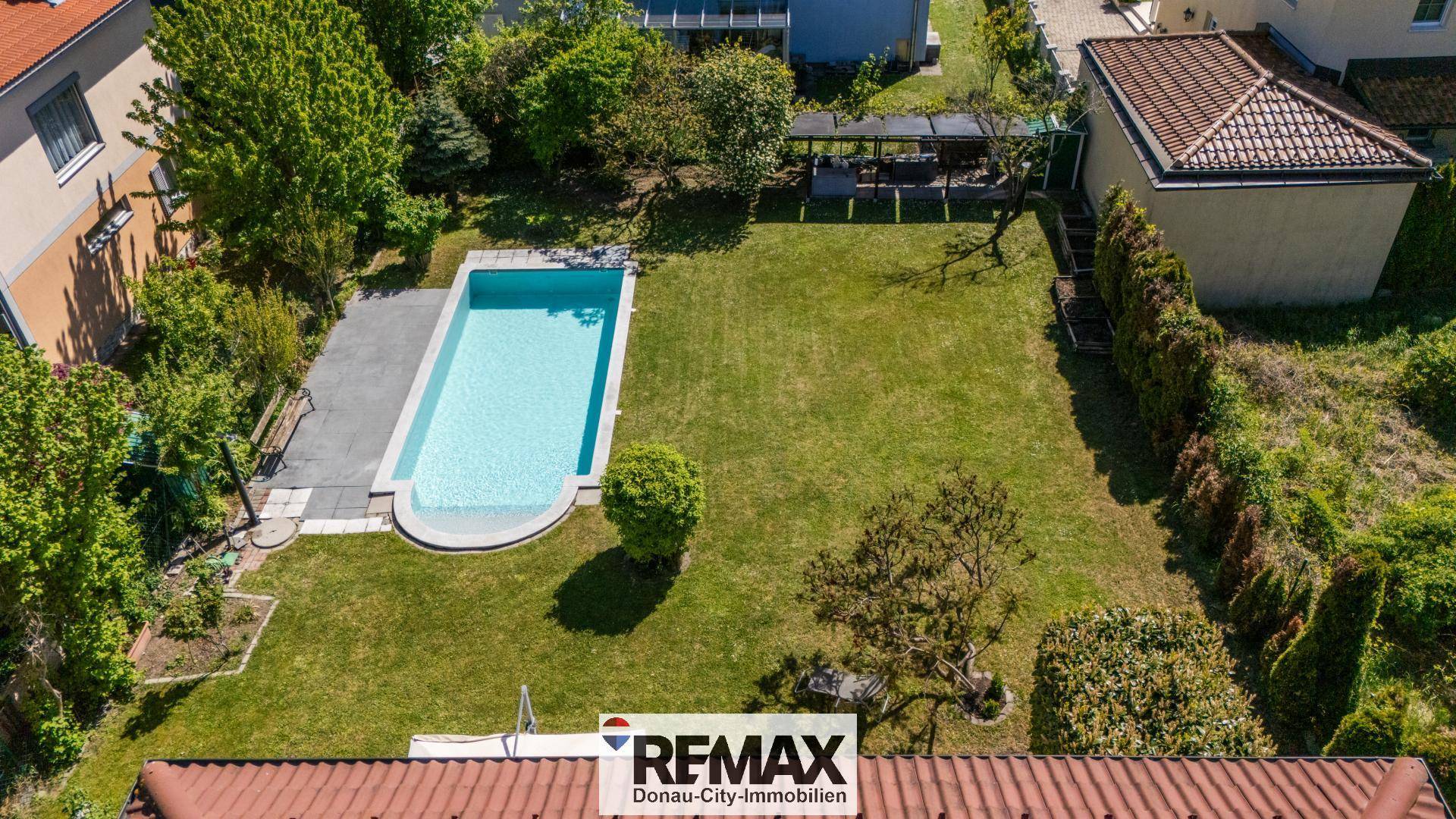 Gepflegter Gartenbereich mit rechteckigem Pool und großer Rasenfläche hinter dem Haus.