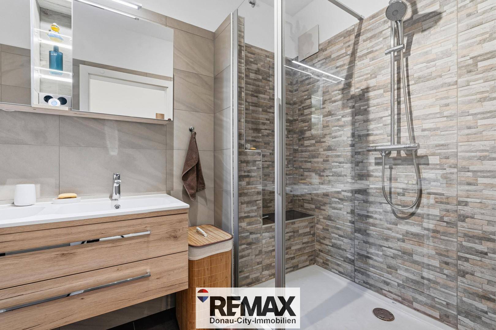 Modernes Badezimmer mit begehbarer Dusche, Einzelwaschbecken und Spiegelschrank.