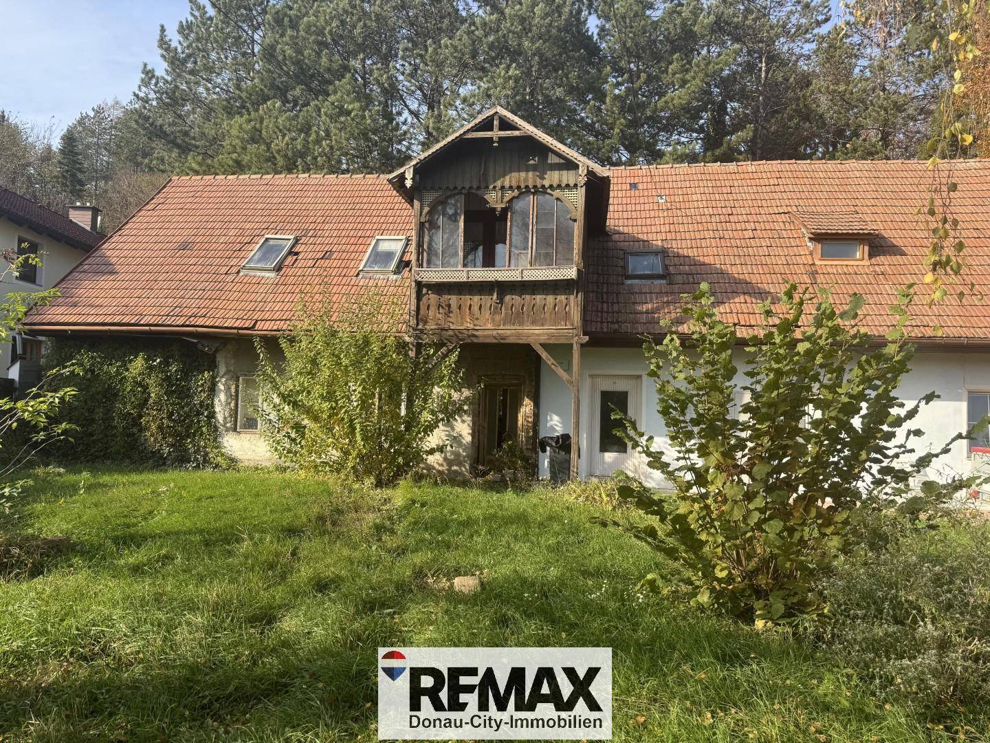 Historisches Haus mit charakteristischem Holzbalkon und großem Gartenbereich.
