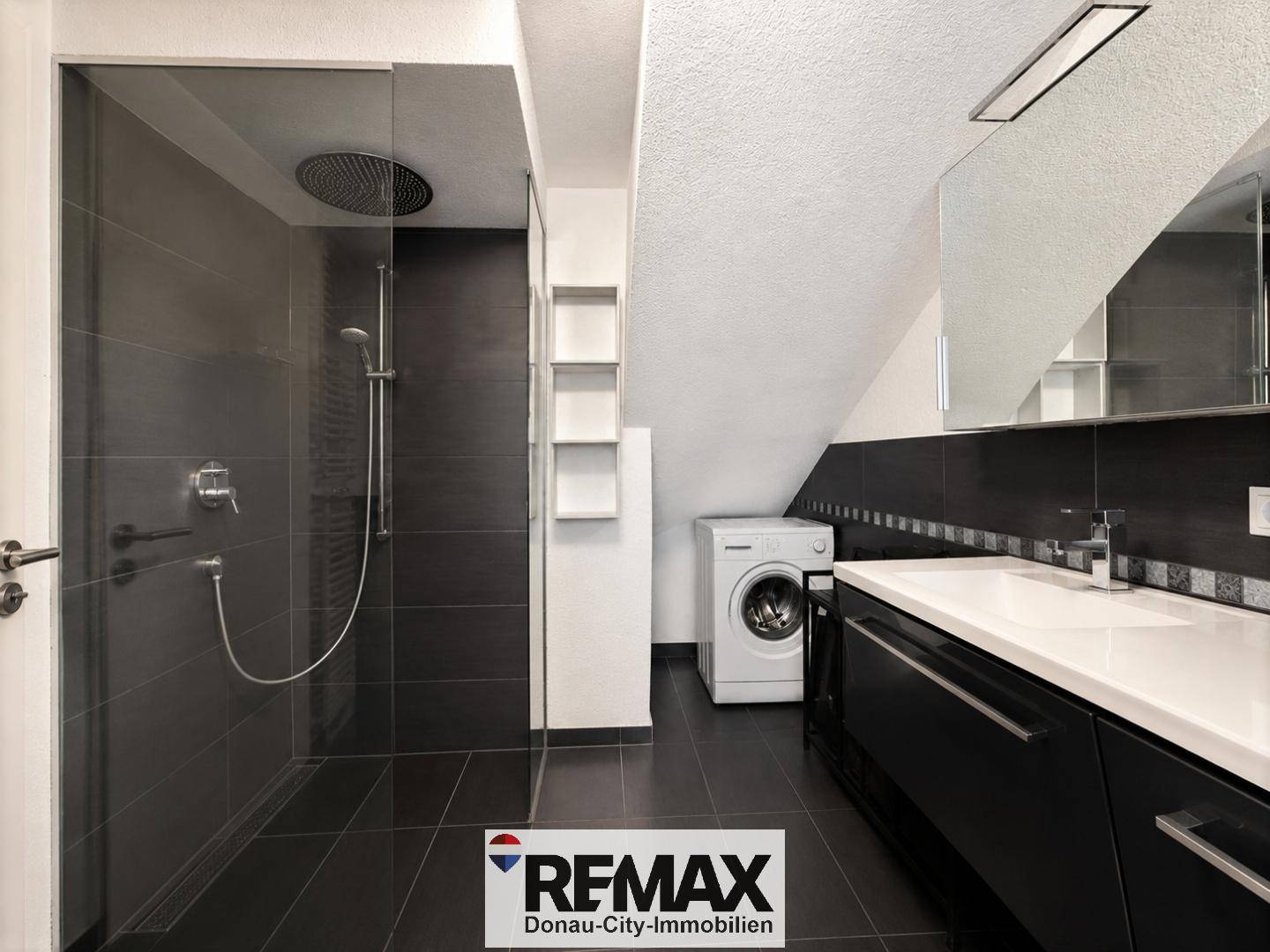 Badezimmer mit großer begehbarer Dusche, Waschmaschine und Dachschräge.