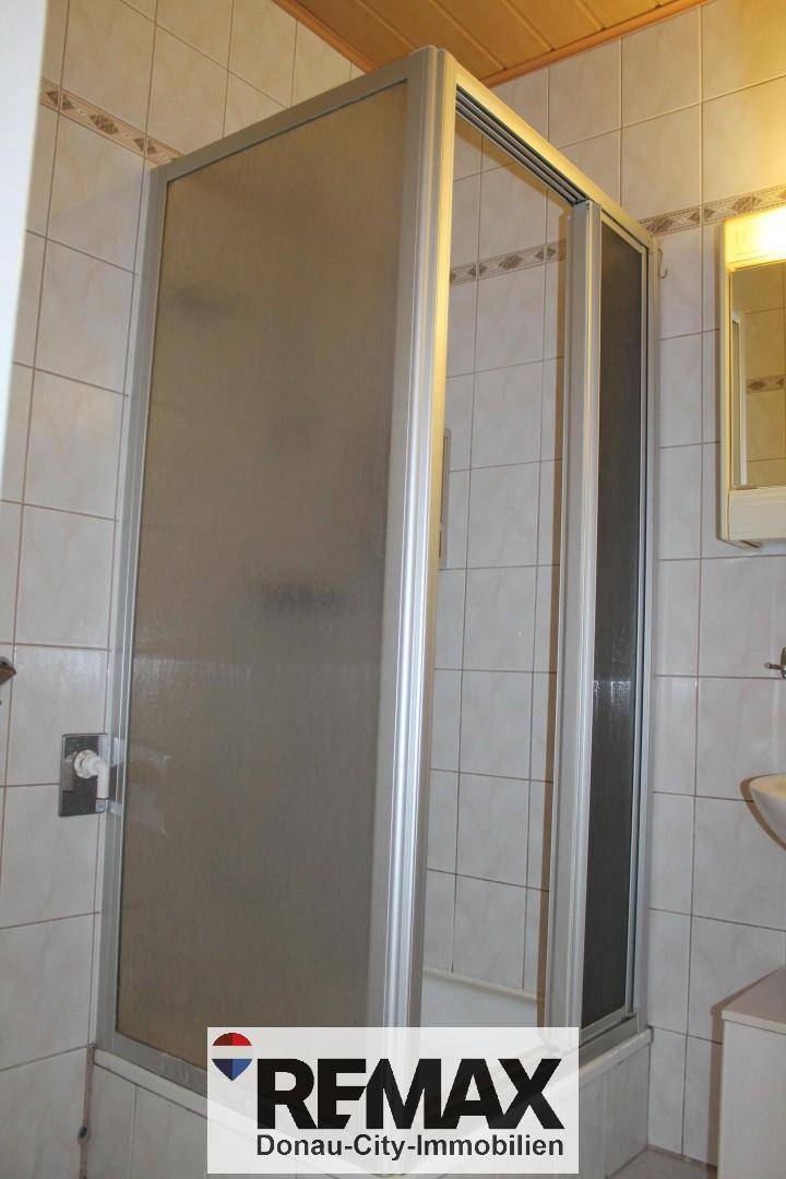 Duschbereich im Badezimmer mit Duschkabine und hellen Fliesen.