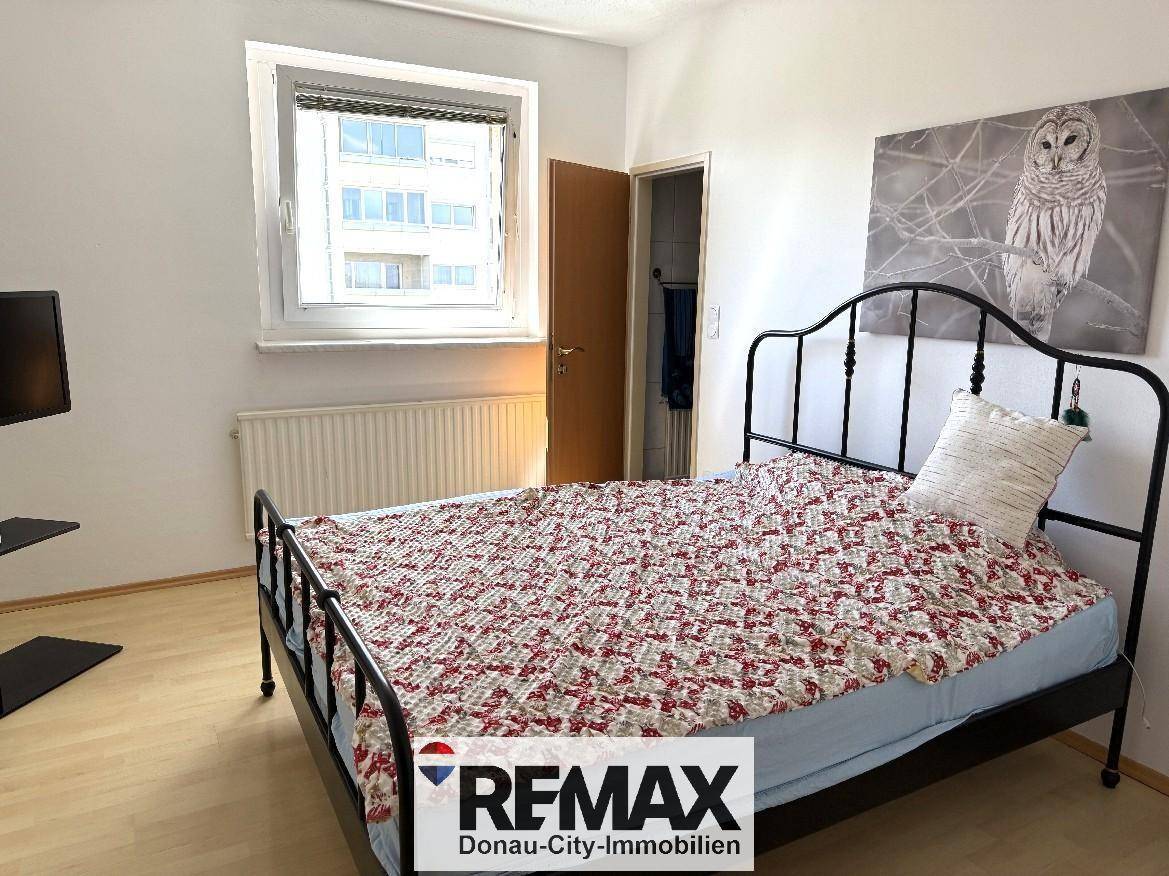 Gemütliches Schlafzimmer mit Fenster, Doppelbett und Laminatboden.