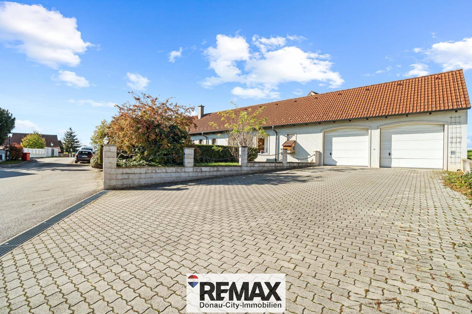 Geräumige Auffahrt mit Pflastersteinen und Doppelgarage vor dem Einfamilienhaus.