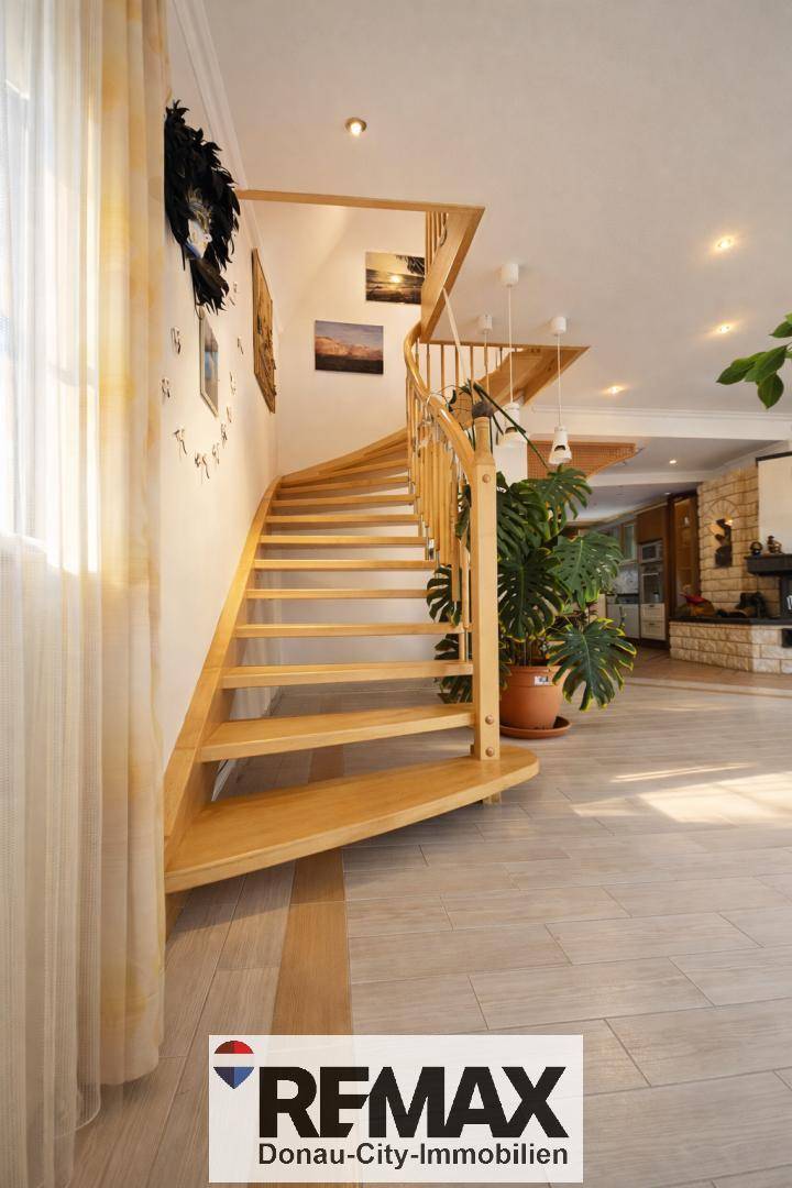 Elegante Holztreppe in einem hellen Raum mit hellem Holzfußboden und einer dekorativen Pflanze.