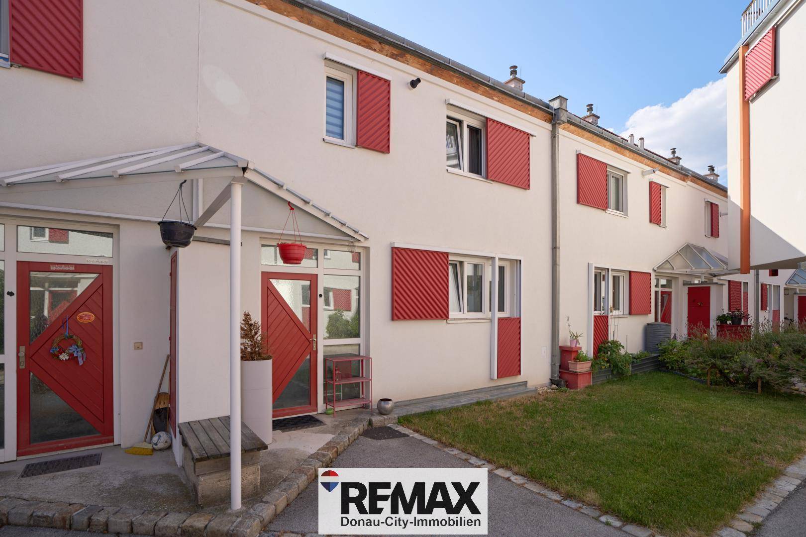 Reihenhäuser mit roten Fensterläden und gepflegtem Vorgarten.