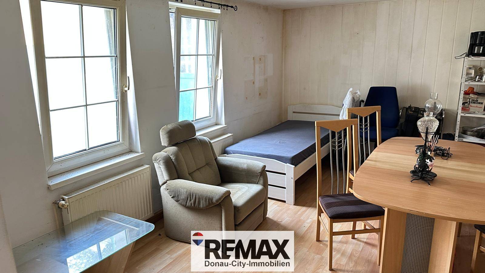 Schlaf- oder Gästezimmer mit Einzelbett, Sessel und Holzfußboden.