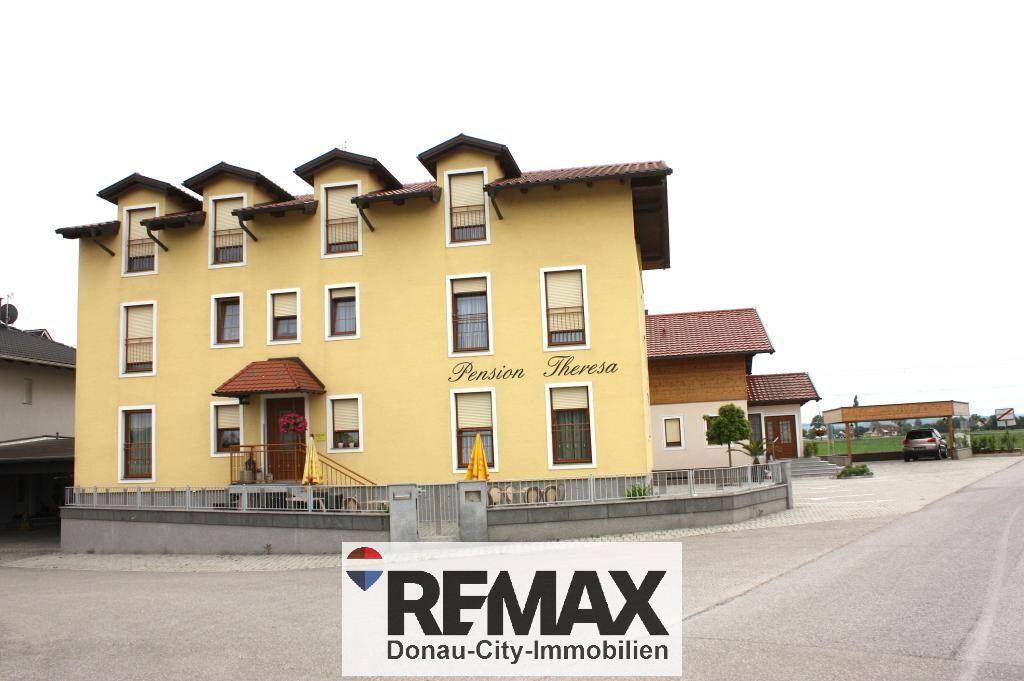Gelbe Fassade eines Gebäudes mit mehreren Fenstern und kleinen Balkonen.