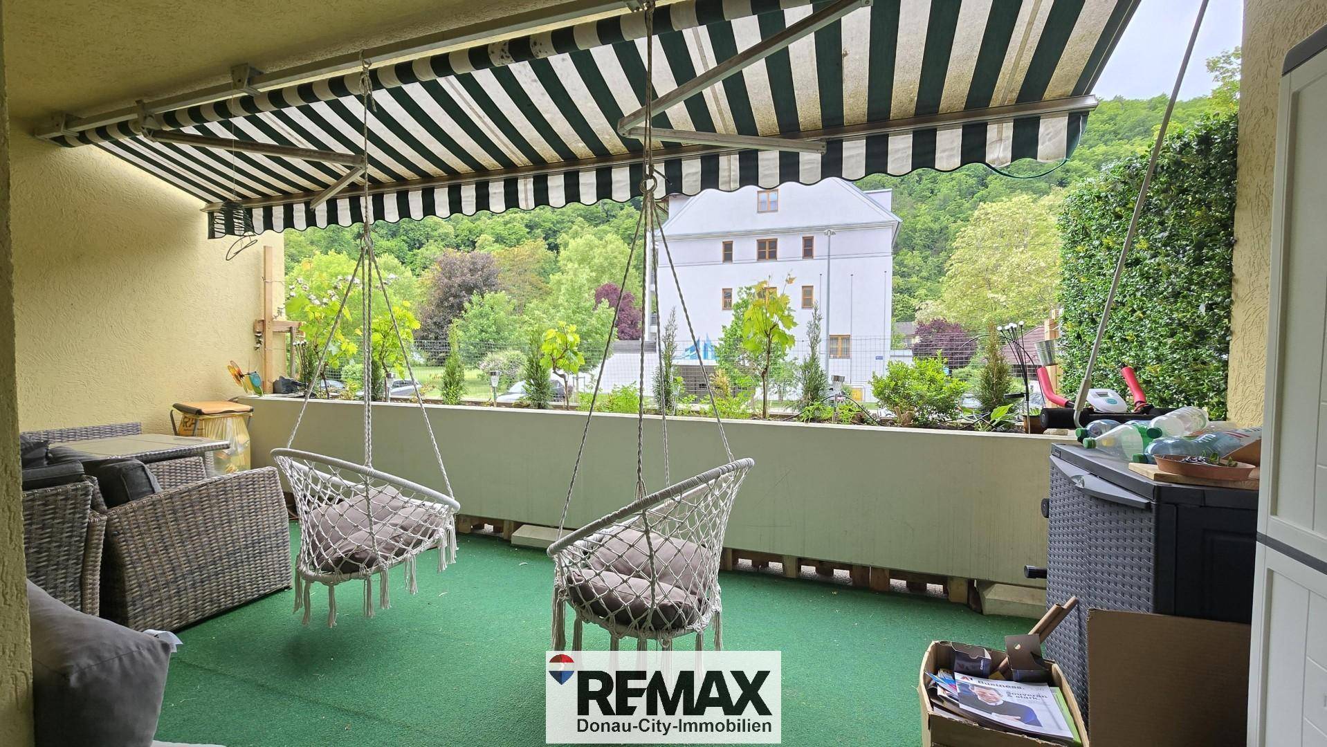 Entspannender Balkon mit Hängesesseln, Markise und Blick auf die umliegende Bebauung und Natur.