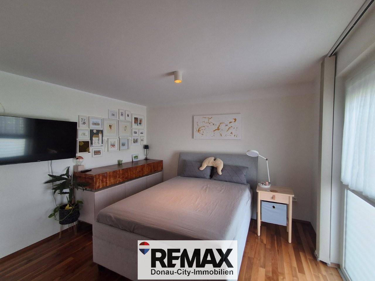 Komfortables Schlafzimmer mit Doppelbett, Holzboden und Wanddekoration.