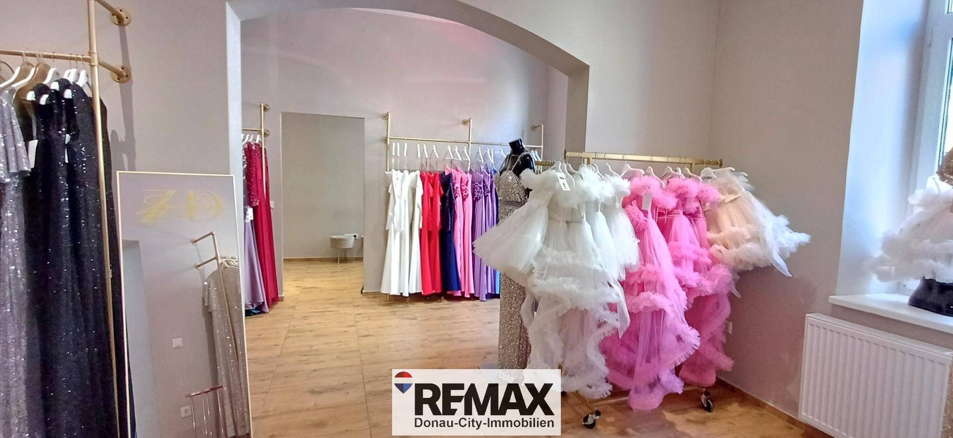 Detailansicht des Verkaufsraums mit Kleiderständern und einer Schaufensterpuppe in einem eleganten Kleid.