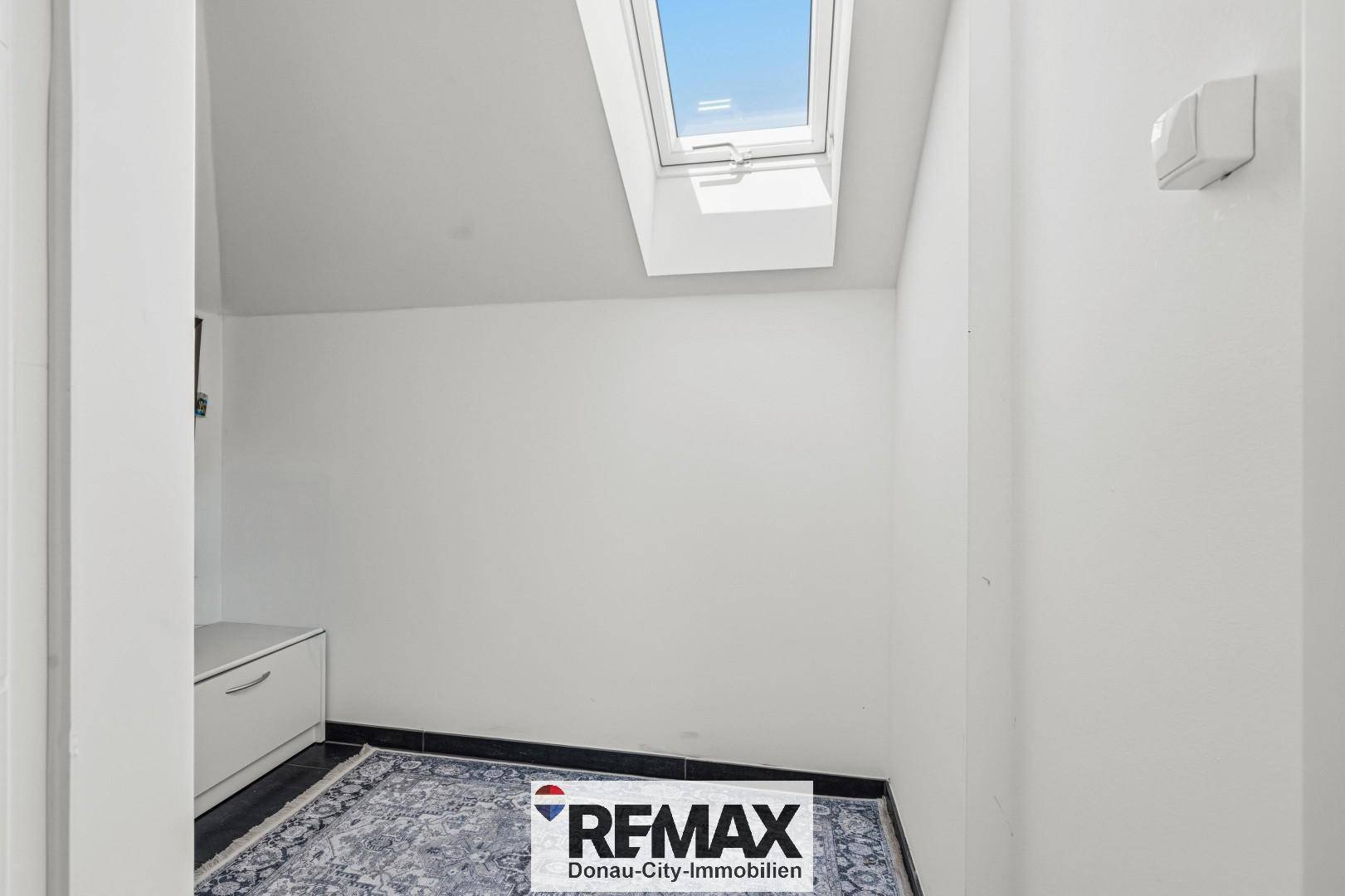 Kleiner Abstellraum mit Dachfenster und Teppichboden, ideal für zusätzlichen Stauraum.