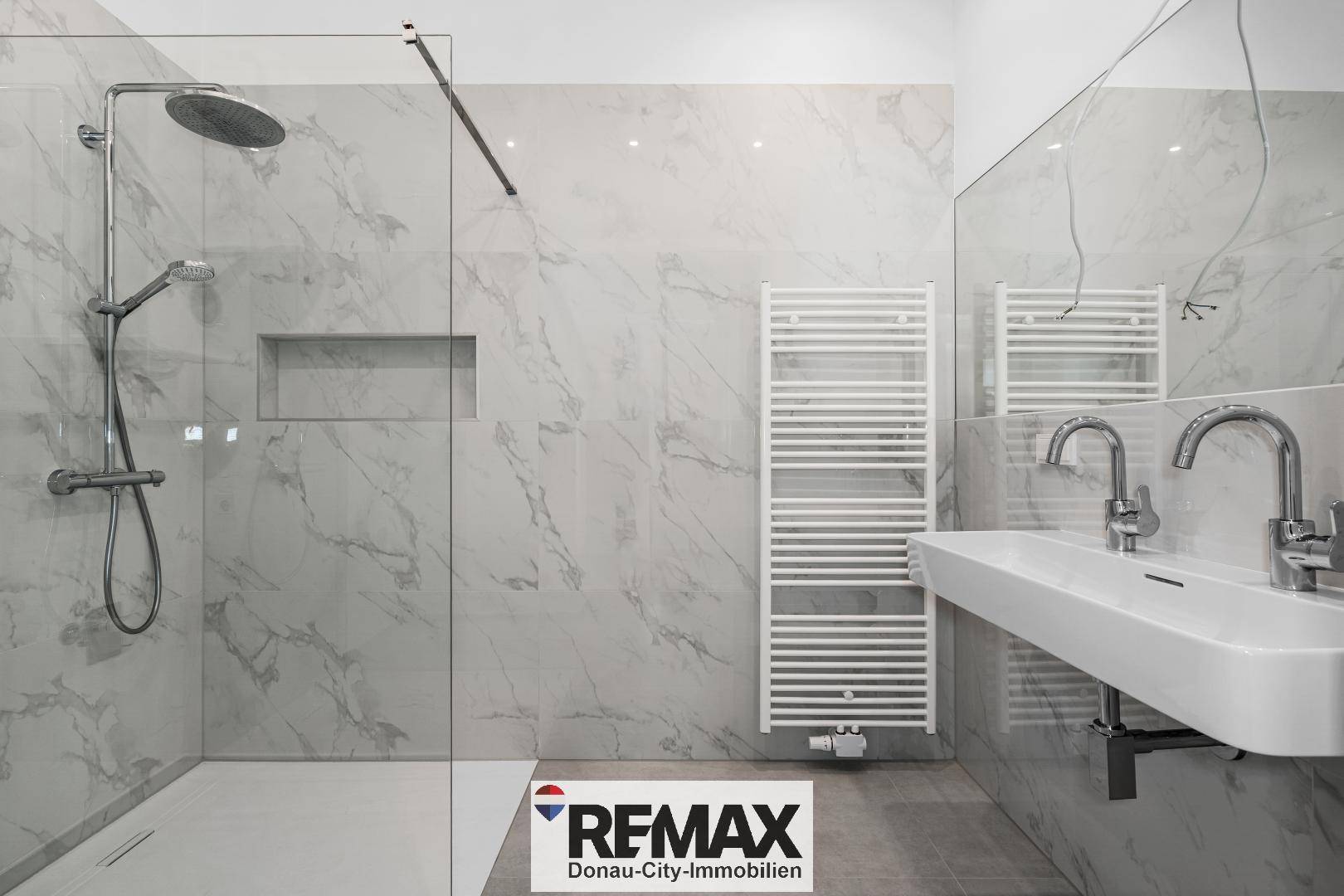 Modernes Badezimmer mit begehbarer Dusche, Doppelwaschbecken und Marmoroptik-Fliesen.