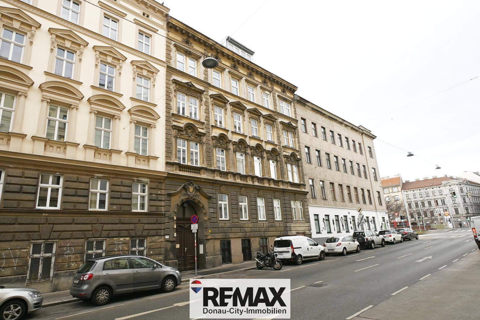 Historische Fassade eines Mehrfamilienhauses an einer belebten Stadtstraße.