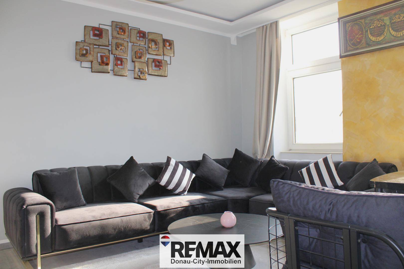 Geräumiges Wohnzimmer mit großem Ecksofa, modernen Wanddekorationen und viel Tageslicht.