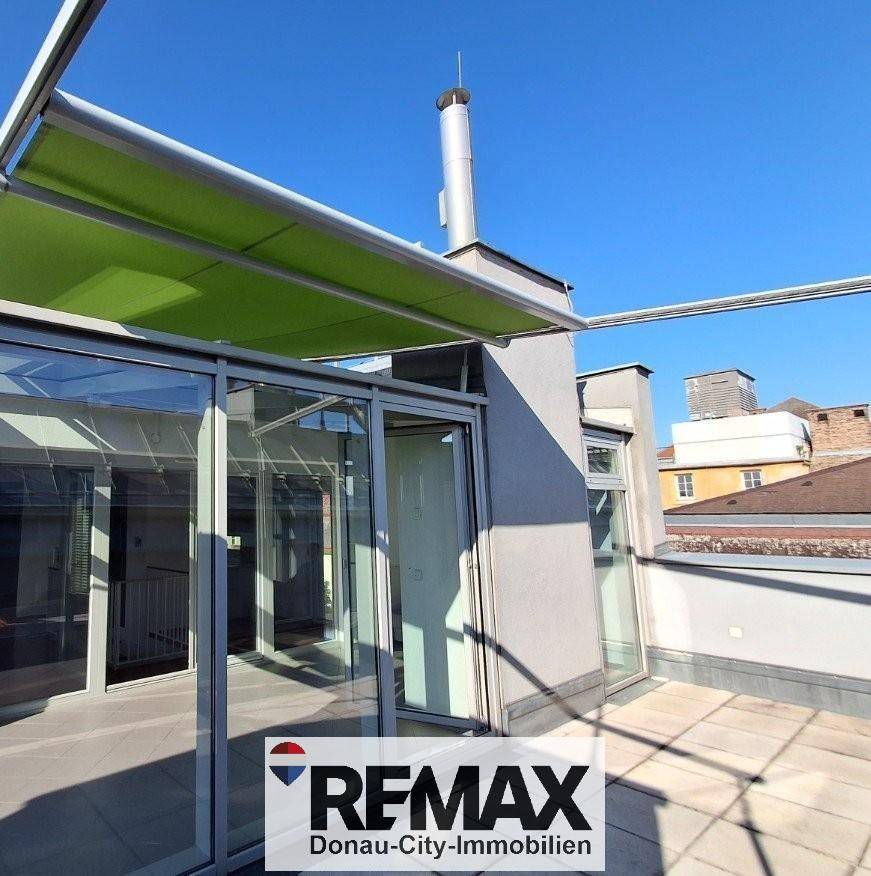 Dachterrasse mit Glasanbau und grüner Markise, ideal für Entspannung im Freien.