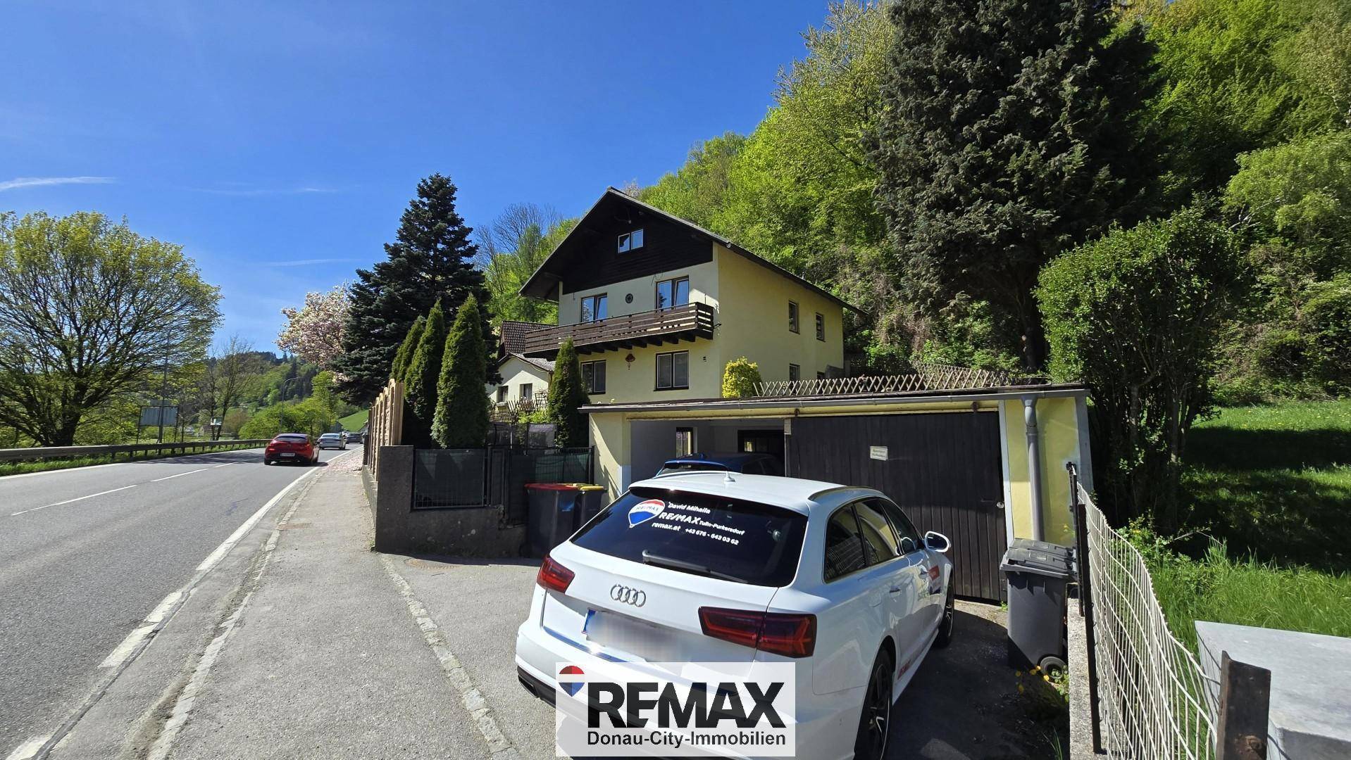 Ansicht des Hauses von der Straße mit einer Garage und einem davor geparkten Auto.