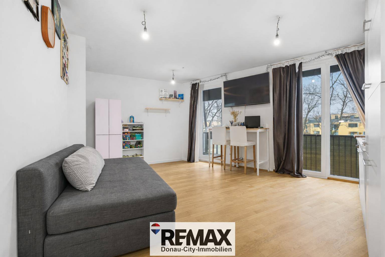 Offener Wohnbereich mit Sofa, Küchenzeile und Zugang zum Außenbereich.