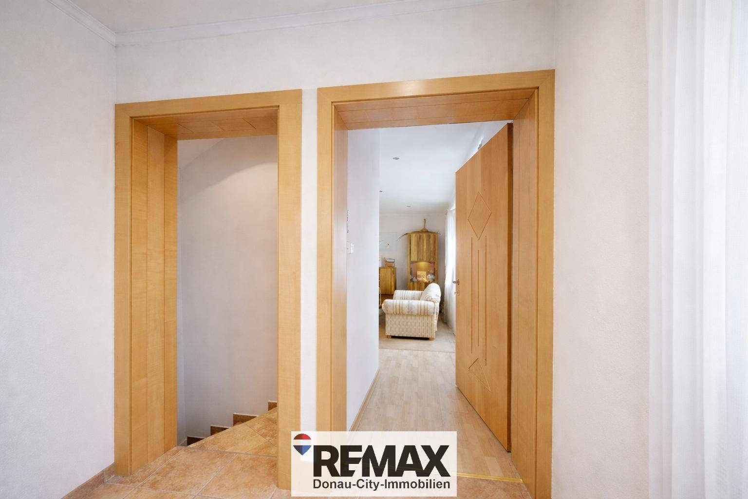 Heller Flur mit Holztüren und Fliesenboden, der zu einem gemütlichen Wohnbereich führt.