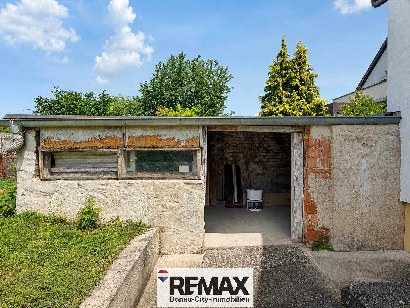 Ältere Garage oder Nebengebäude mit Renovierungsbedarf und sichtbaren Abnutzungsspuren.