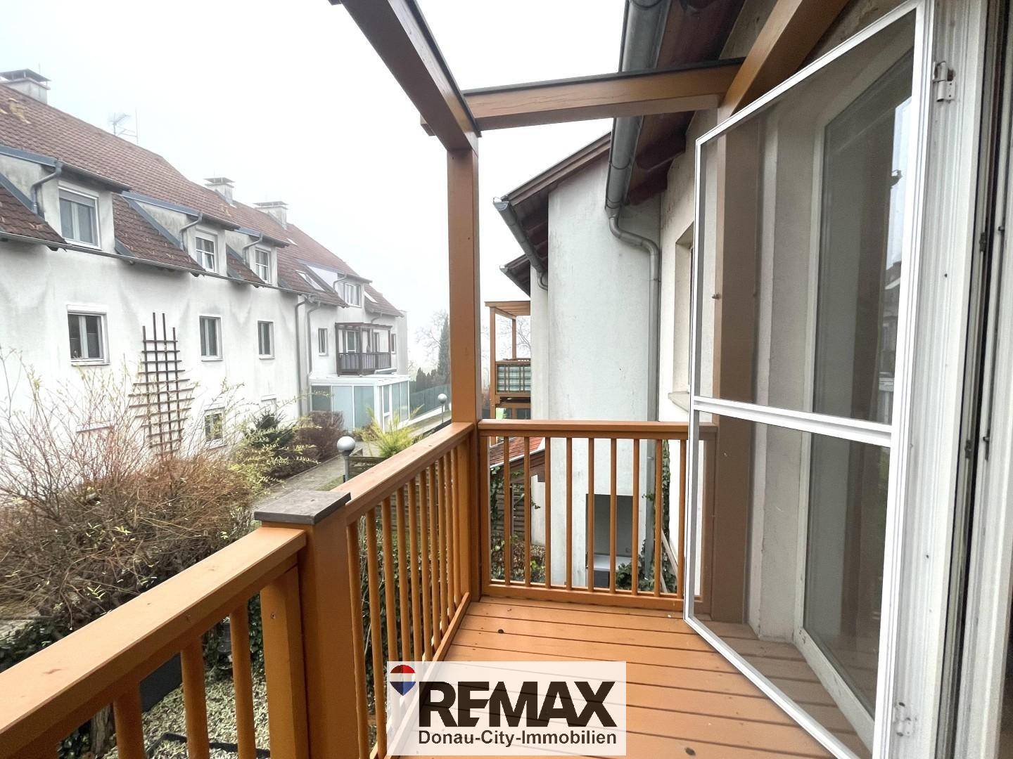 Holzbalkon mit Blick auf die Nachbarschaft und weitere Balkone.
