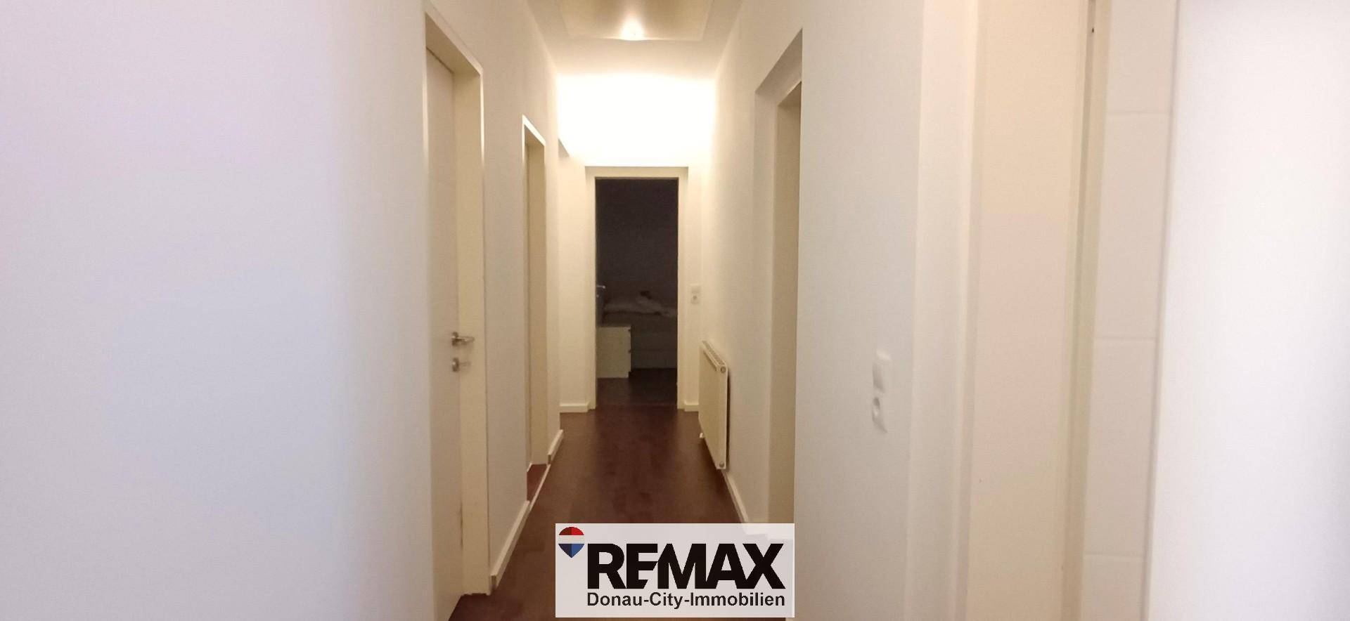 Langer Flur mit Holzboden und Zugang zu verschiedenen Zimmern der Wohnung.