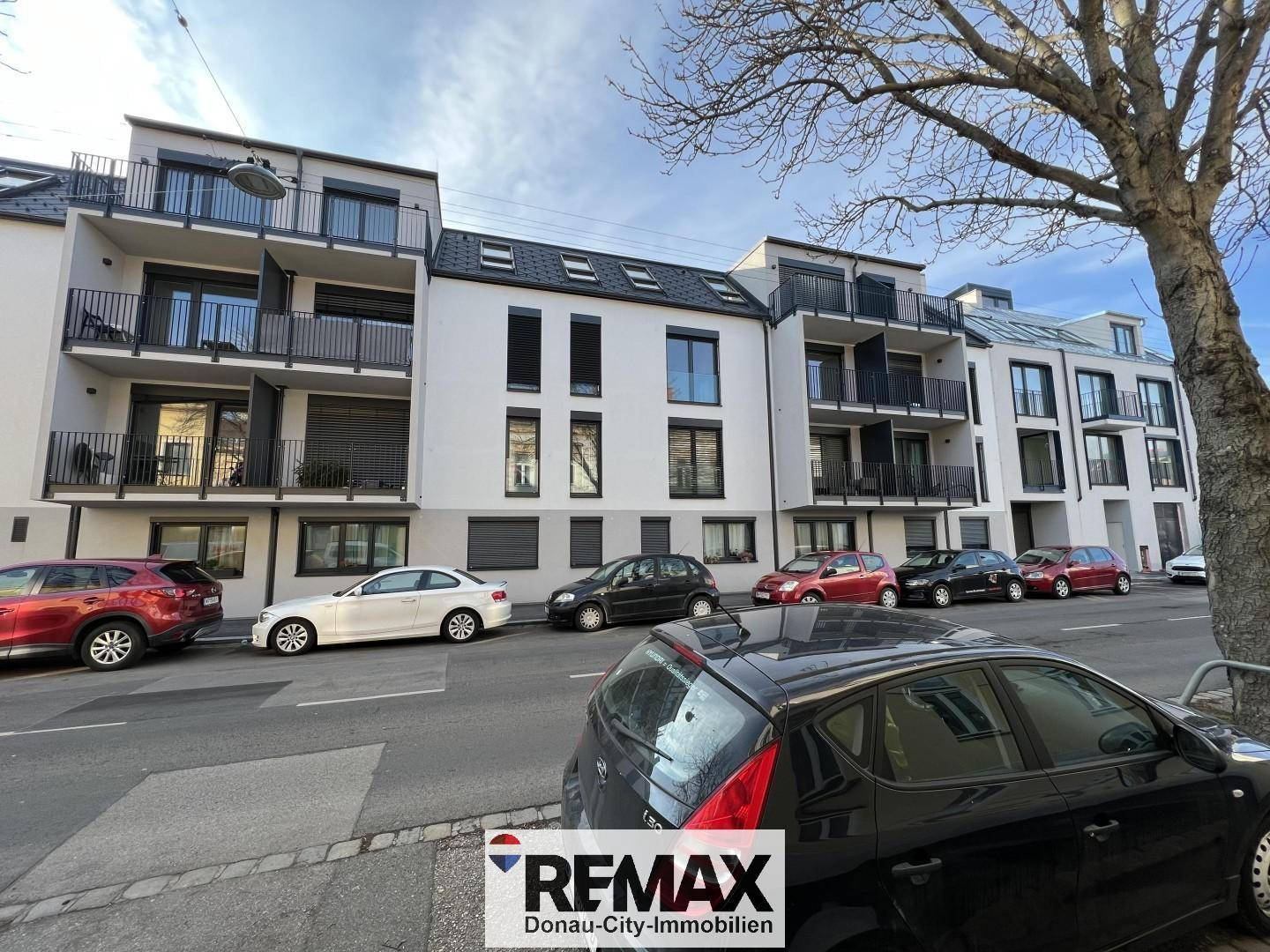 Moderne Wohngebäude mit Balkonen und großen Fenstern entlang einer städtischen Straße.