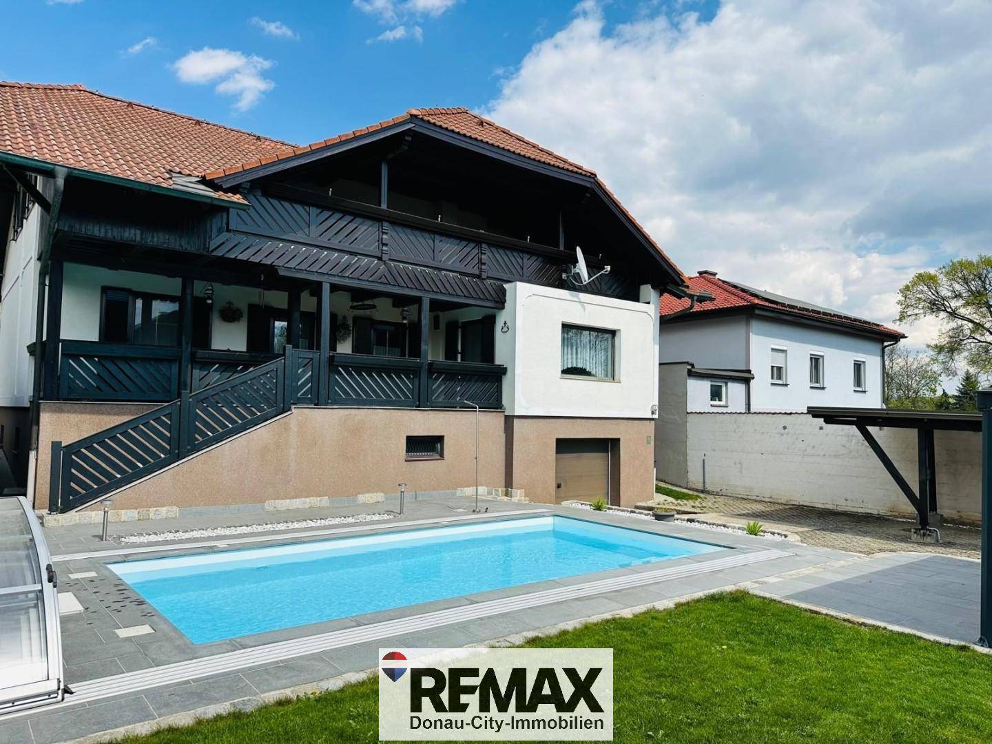 Außenansicht des Hauses mit großem Swimmingpool und gepflegtem Rasenbereich.