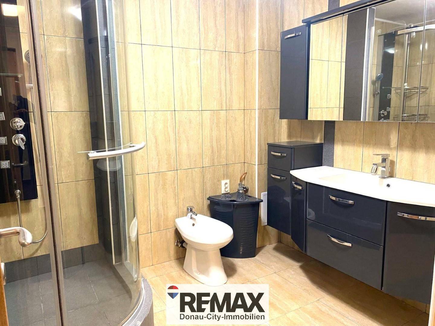 Badezimmer mit Duschkabine, Bidet und modernem Waschtisch mit Unterschrank.