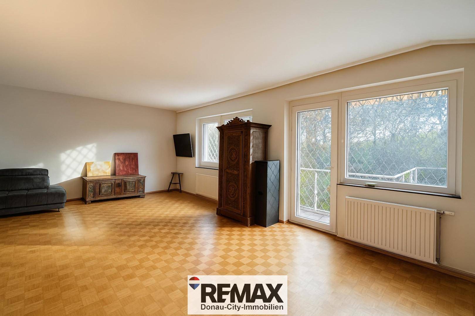 Helles Wohnzimmer mit Parkettboden, antiken Möbeln und Zugang zum Balkon.