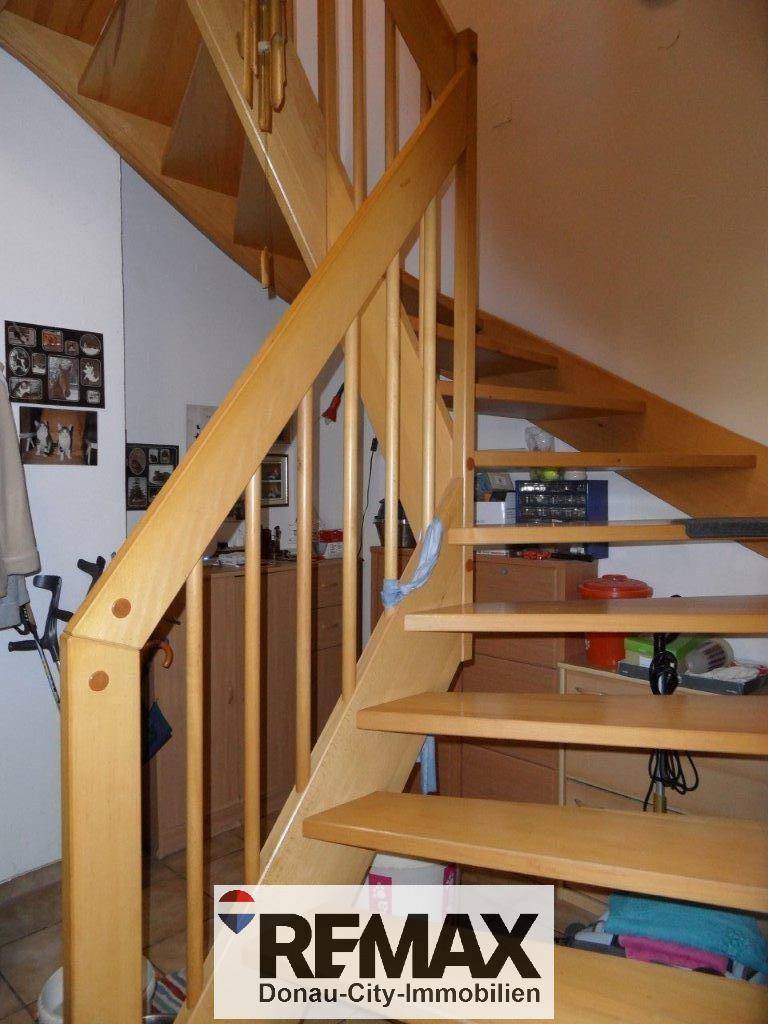 Helle Holztreppe, die die verschiedenen Ebenen des Hauses miteinander verbindet und einladend wirkt.