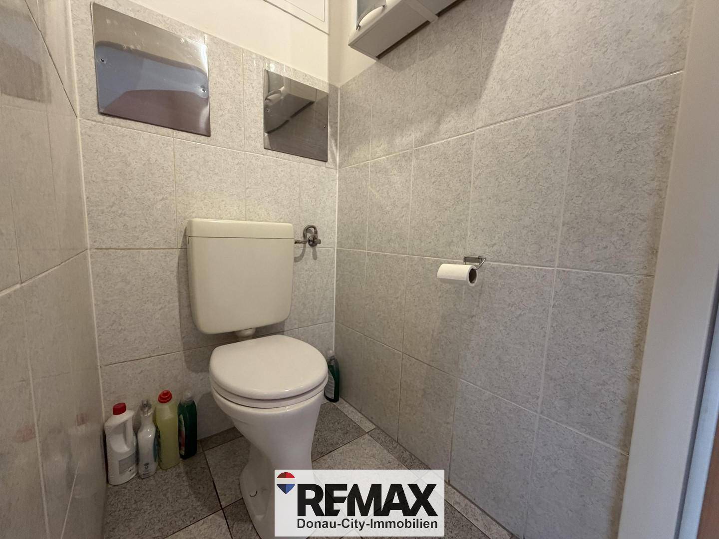 Separate Toilette mit Fliesen an Wänden und Boden.