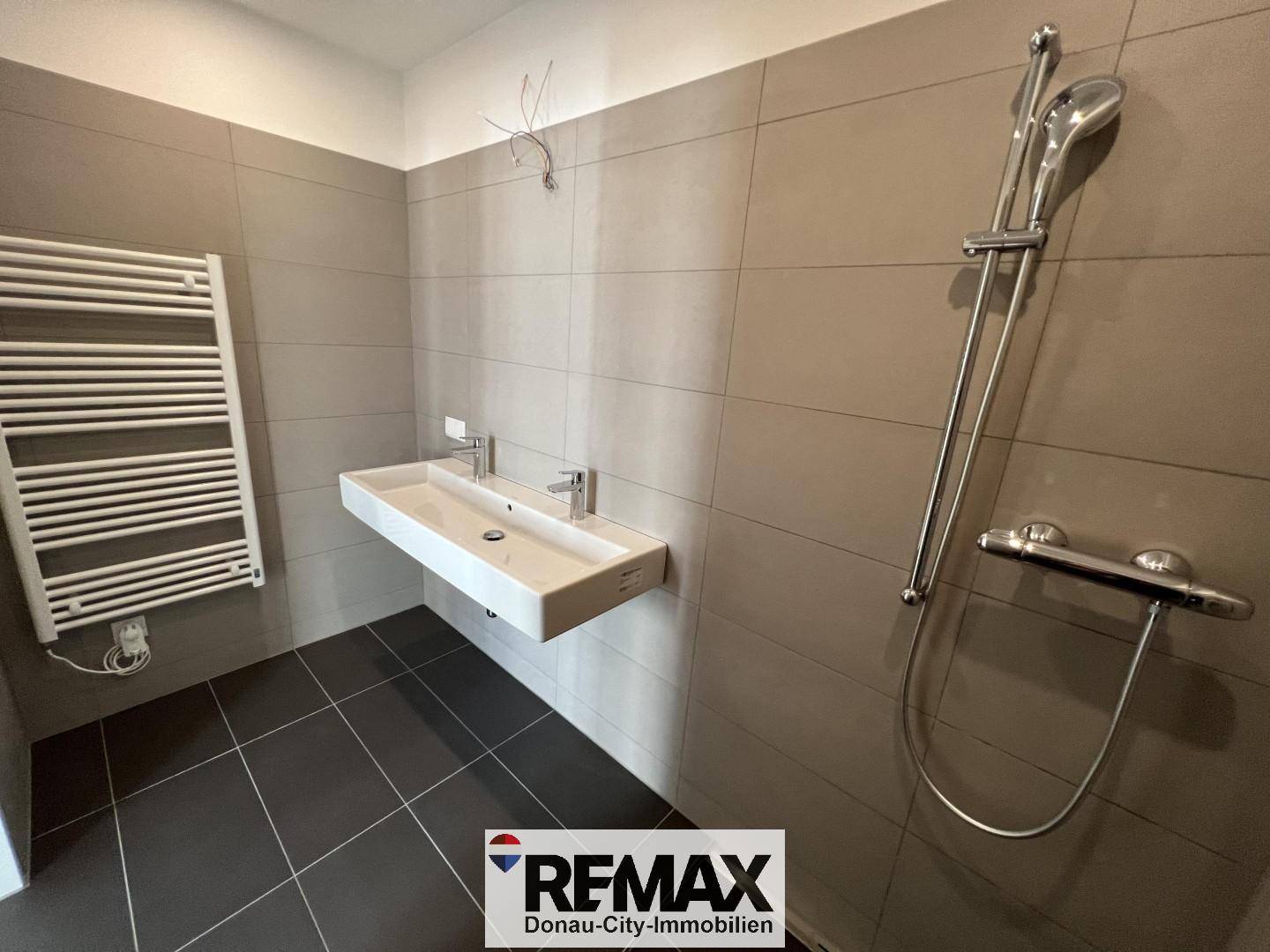 Geräumiges Badezimmer mit Doppelwaschbecken, Duschbereich und modernem Handtuchheizkörper.
