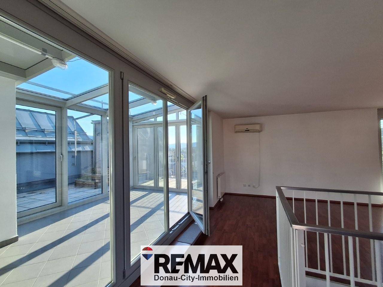 Unmöblierter Wintergarten mit Glaswänden, Klimaanlage und Zugang zu einer sonnigen Dachterrasse.