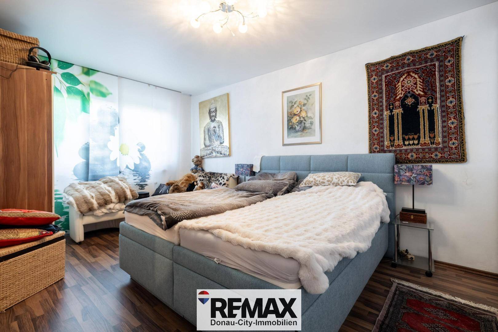 Schlafzimmer mit Doppelbett, Holzboden und orientalischen Dekorationselementen.