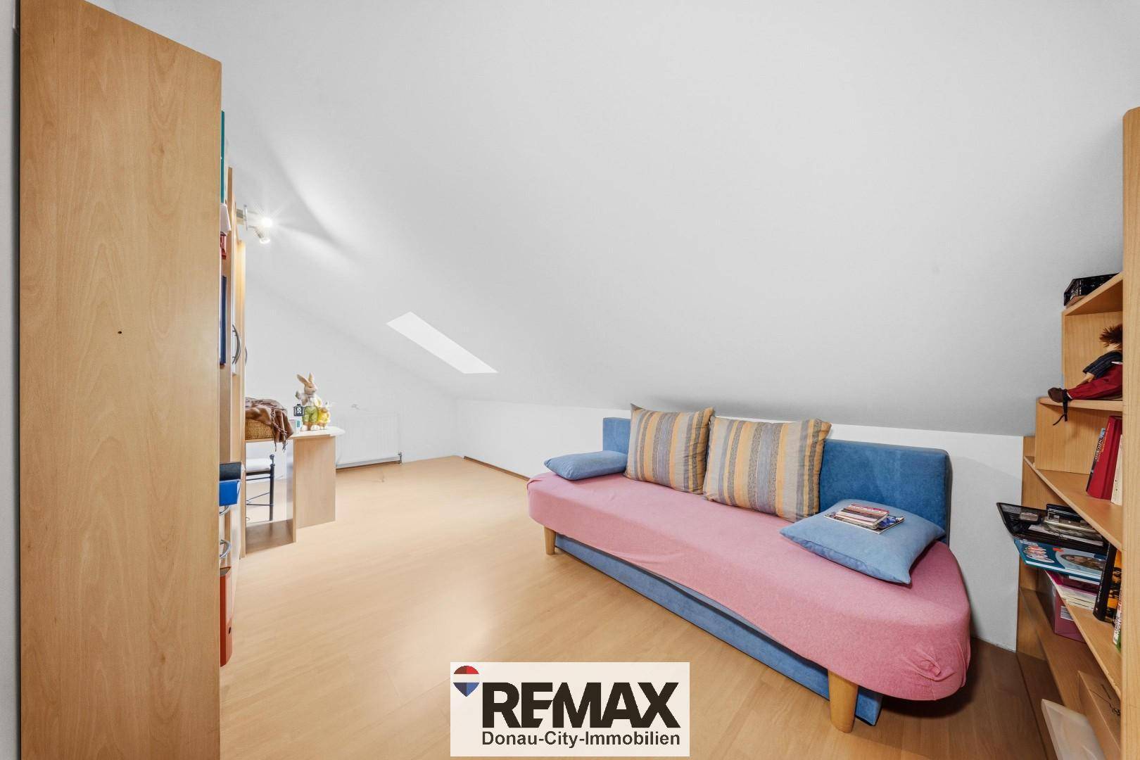 Helles Dachgeschosszimmer mit Schlafsofa, Regal und Dachfenster, vielseitig nutzbar.