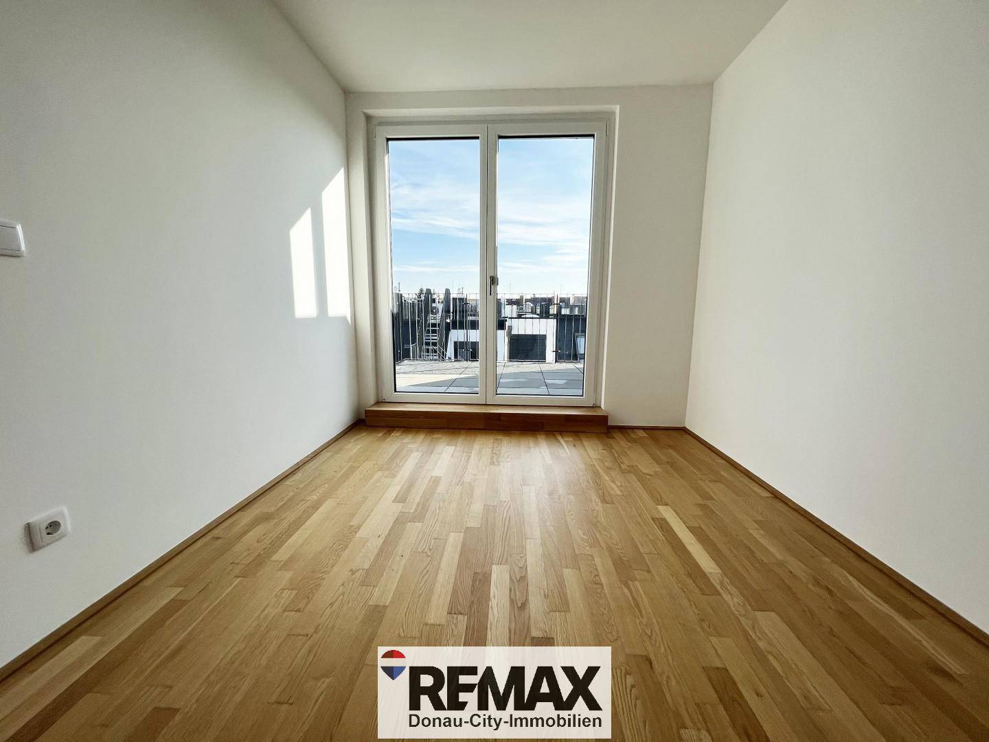 Leerer Raum mit Holzboden und großen Fenstern, ideal als Esszimmer oder zusätzliches Wohnzimmer.