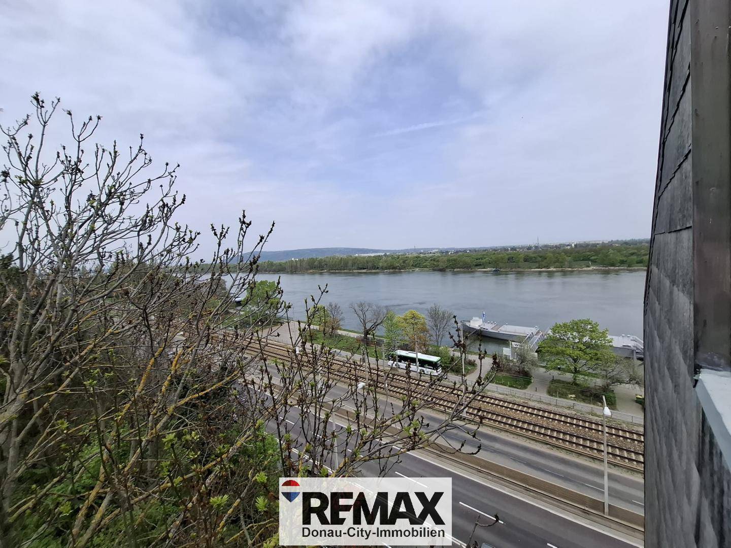 Weitblick über den Fluss und die Stadt mit Bahngleisen und Straße im Vordergrund.