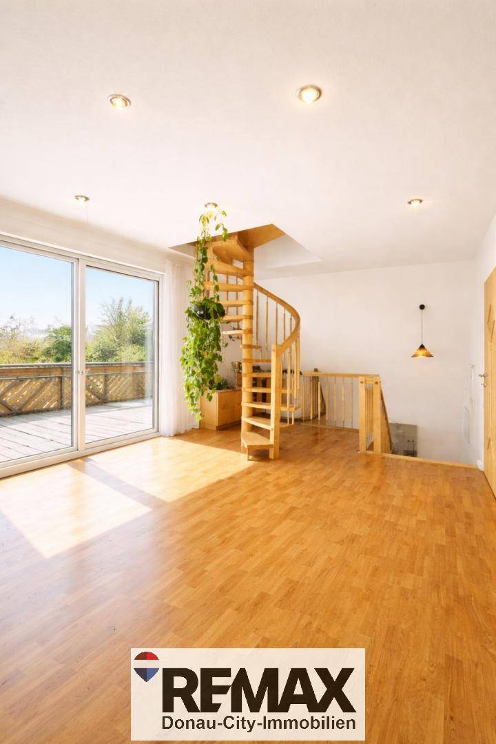 Geräumiger Wohnbereich mit Holzwendeltreppe, großer Glasschiebetür zur Terrasse und hellem Holzfußboden.
