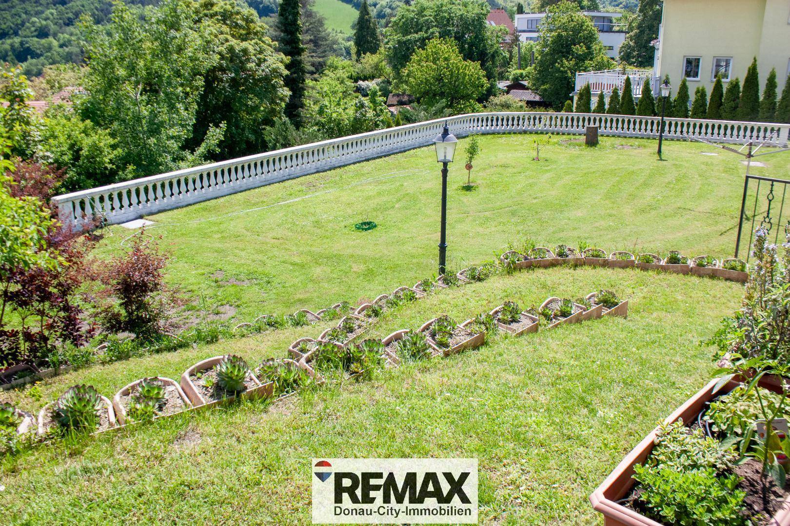 Terrassierter Gartenbereich mit Rasen, Blumenbeeten und einer Balustrade mit weitem Blick.